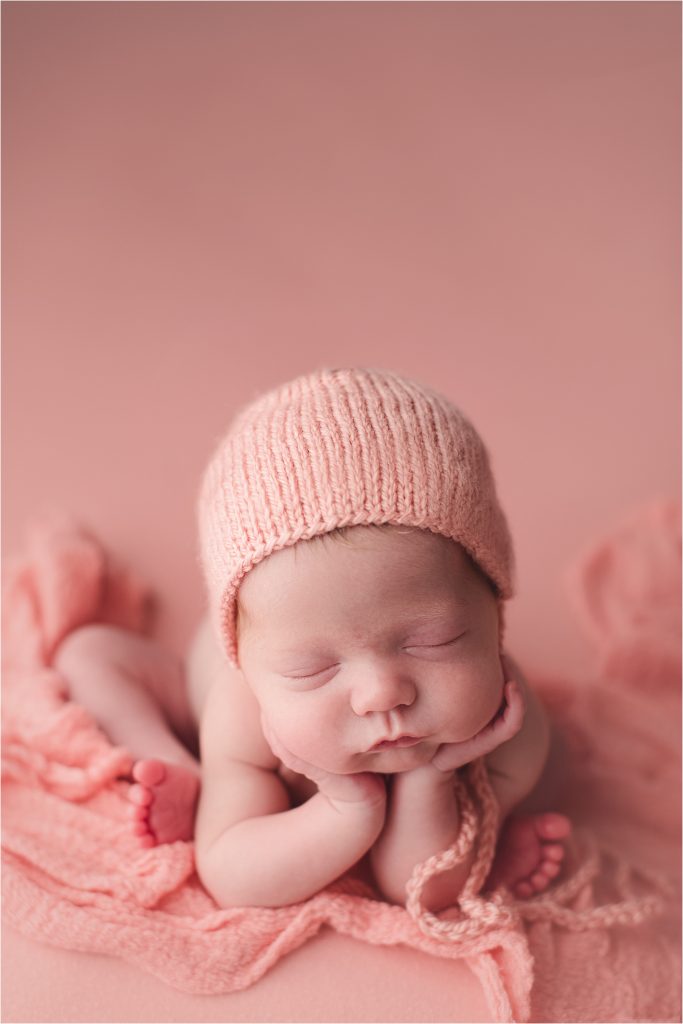 baby girl on coral backdrop in froggie pose