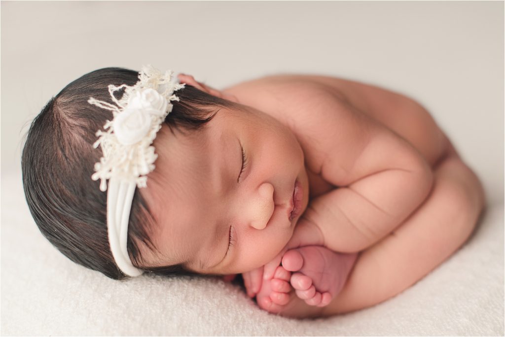 baby girl in womb pose on white lace