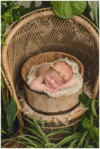 baby girl in farmhouse bucket prop surrounded by plants