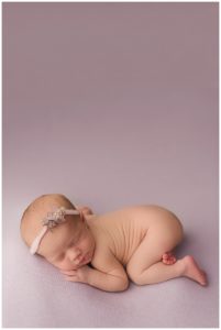 baby girl on lavendar backdrop in tummy time pose
