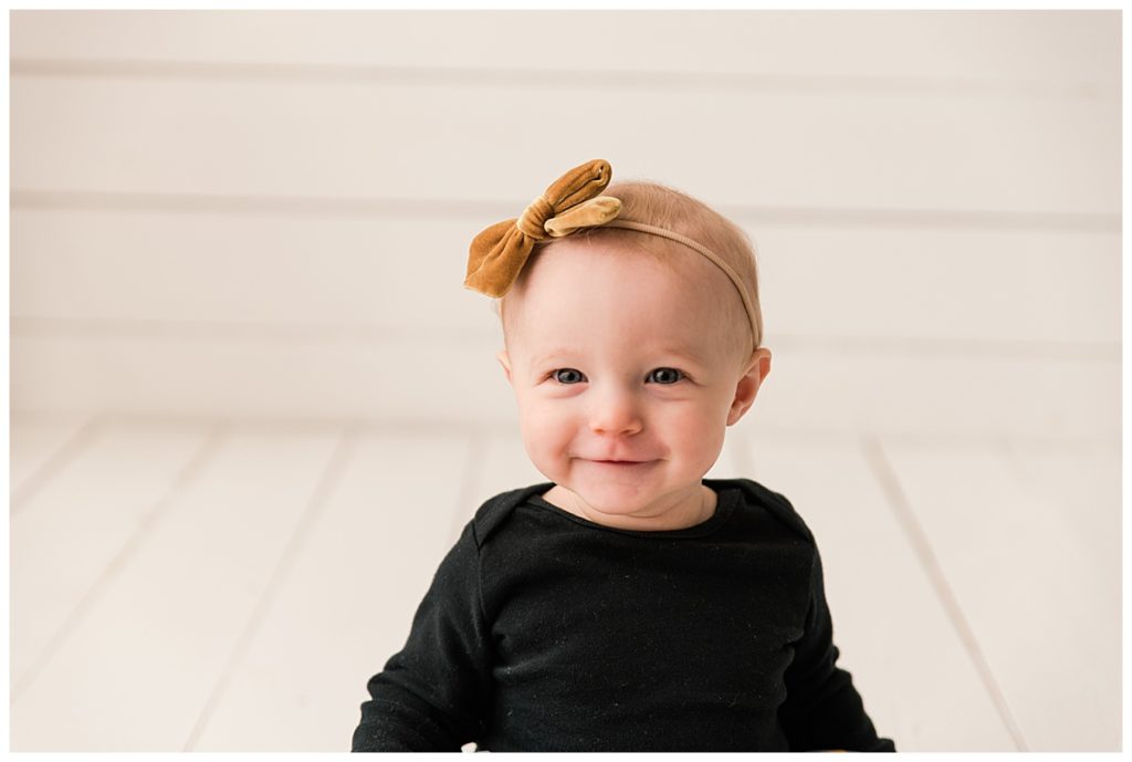 Baby girl grinning with black velvet shirt with gold bow