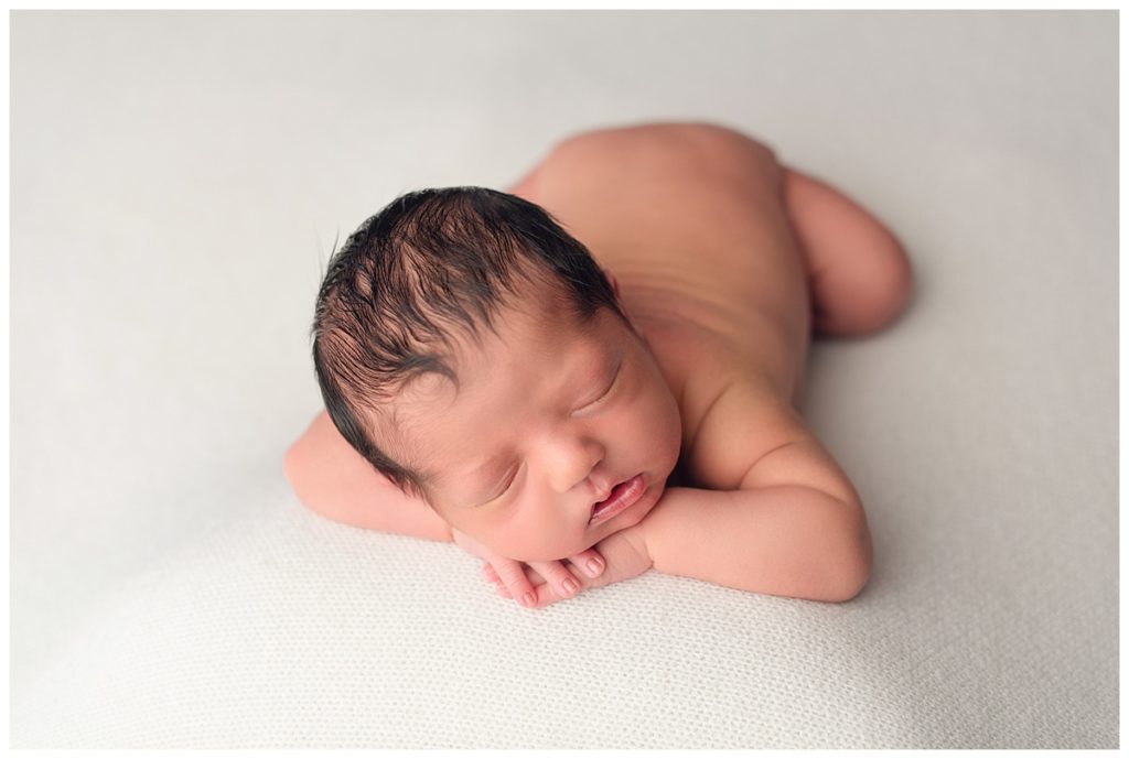 baby boy with lots of hair on head on hands on white backdrop