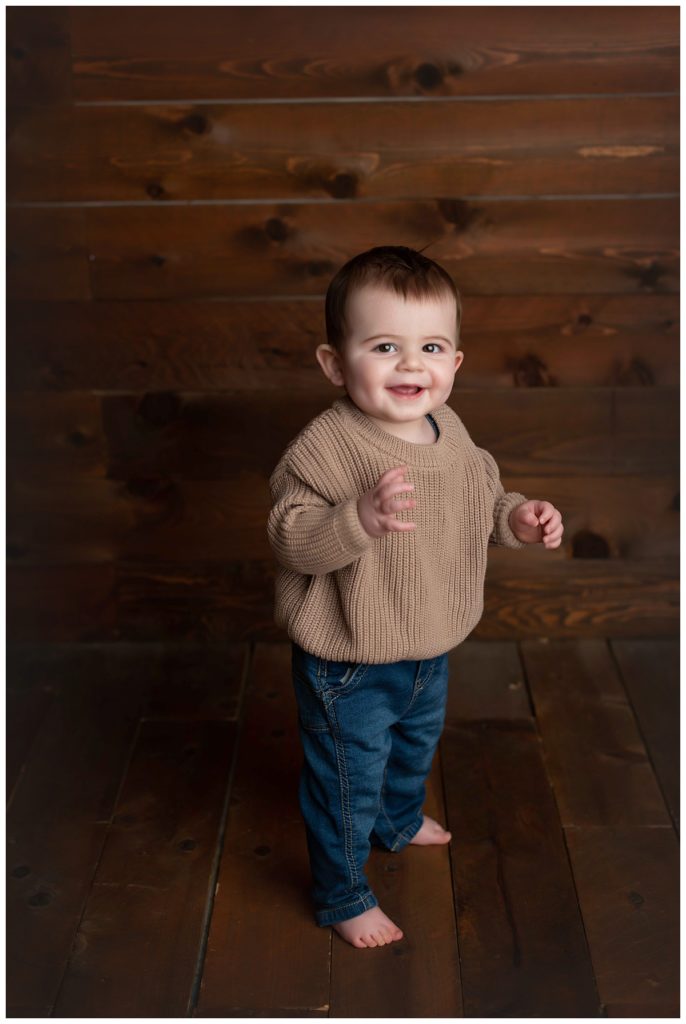 baby boy standing on wood backdrop