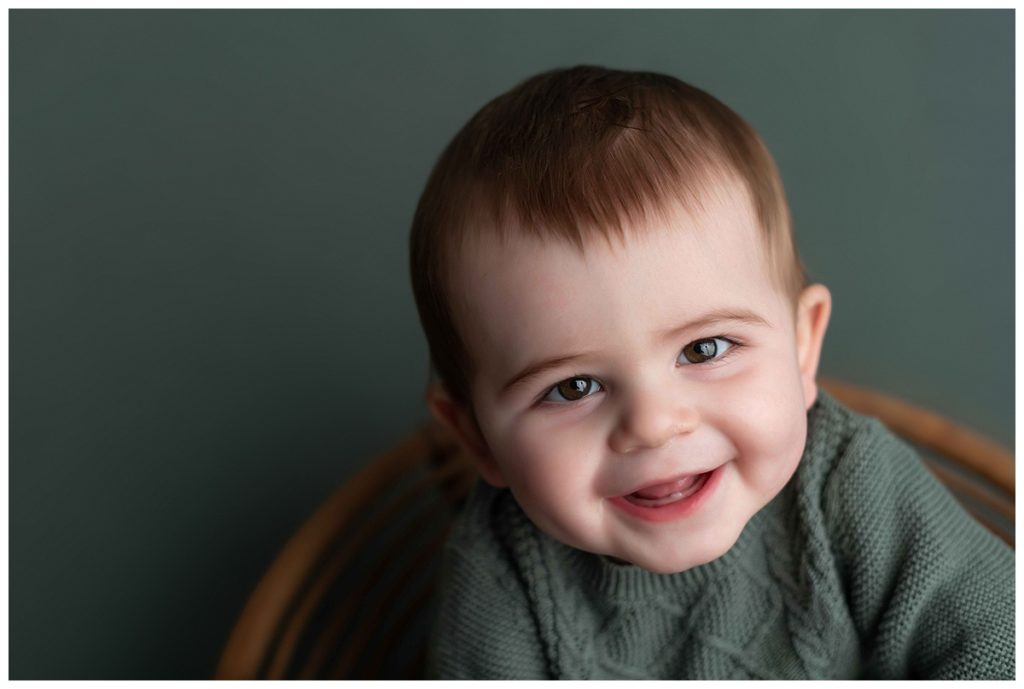 close up of baby boy in green outfit from target on green backdrop