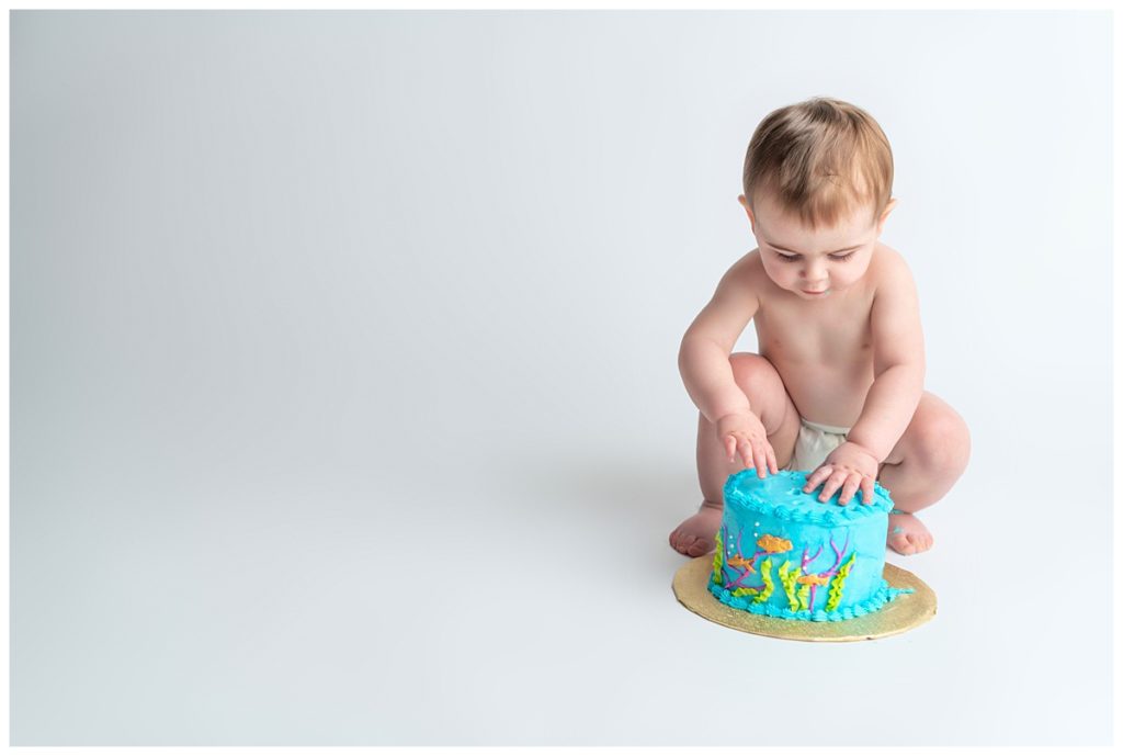 baby boy looking at his blue cake smash