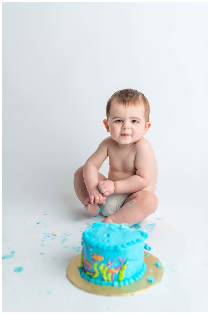 baby boy eating blue cake making ornery face