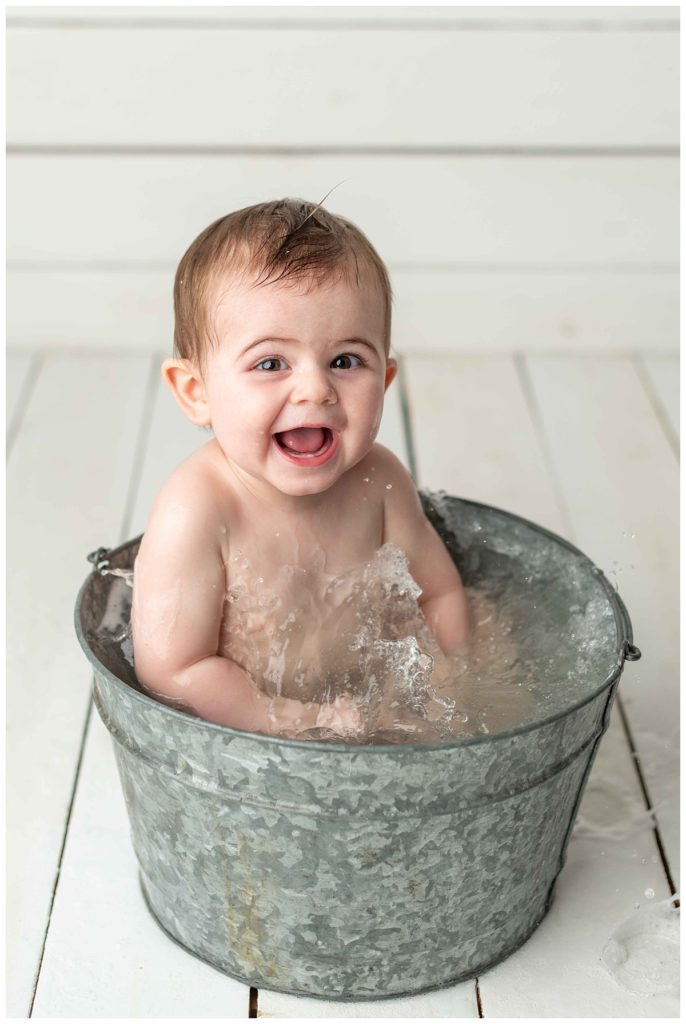 baby boy looking at camera and laughing in basin