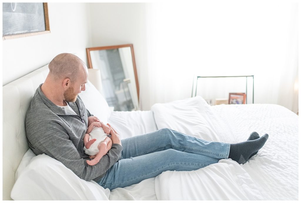 dad holding baby on bed