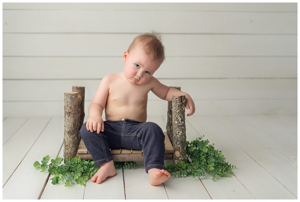 19 month old boy exasperated with photographer, leaning on prop