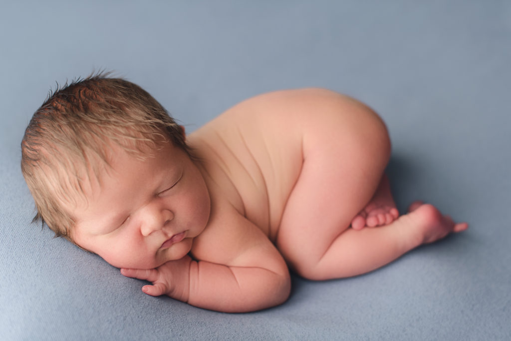 baby boy on muted blue backdrop with chunky rolls