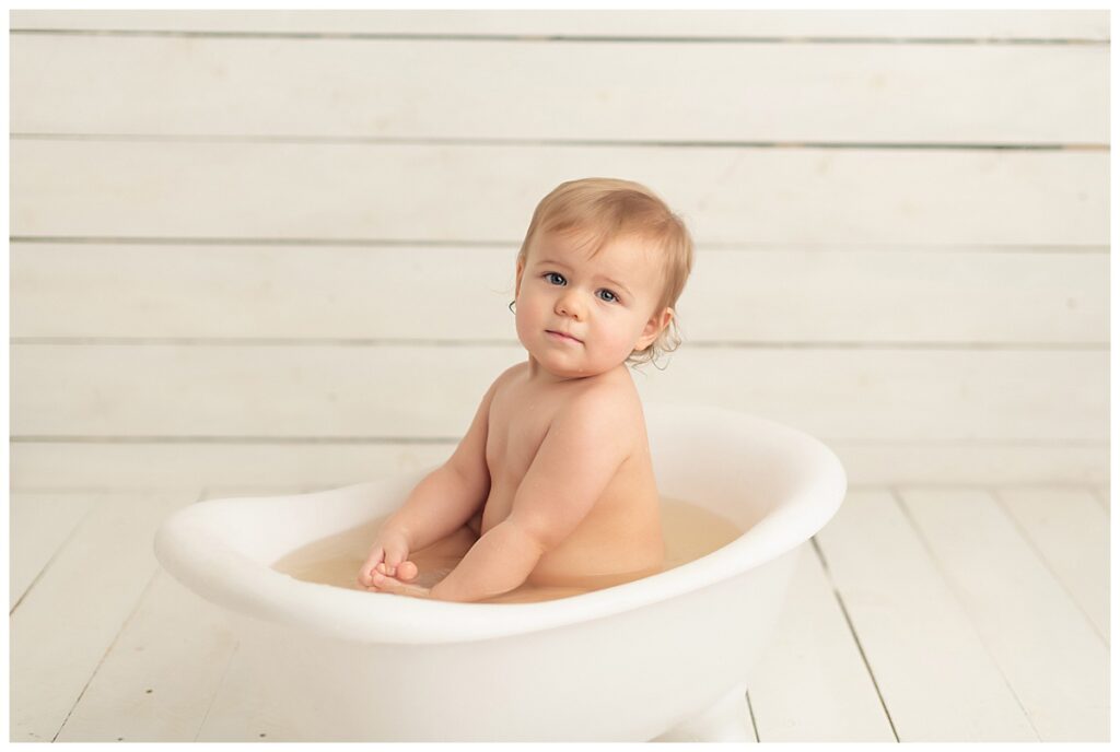 Baby girl looking right at camera in baby sized claw foot tub