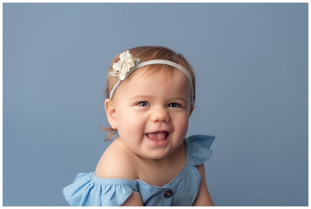 Baby girl smiling on blue backdrop
