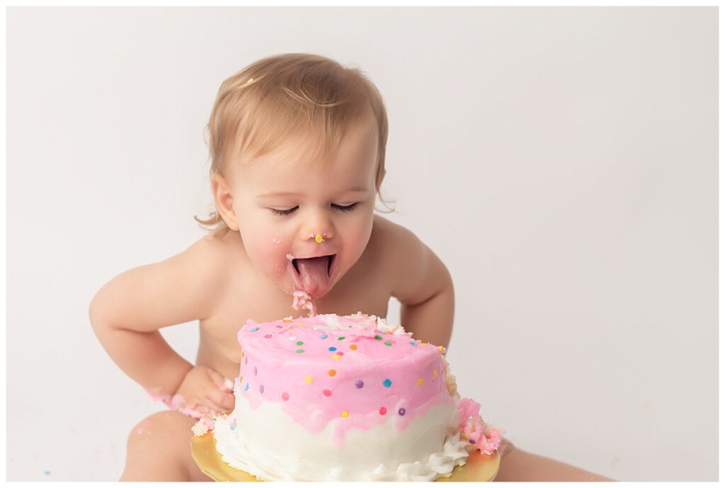 Baby girl licking her cake