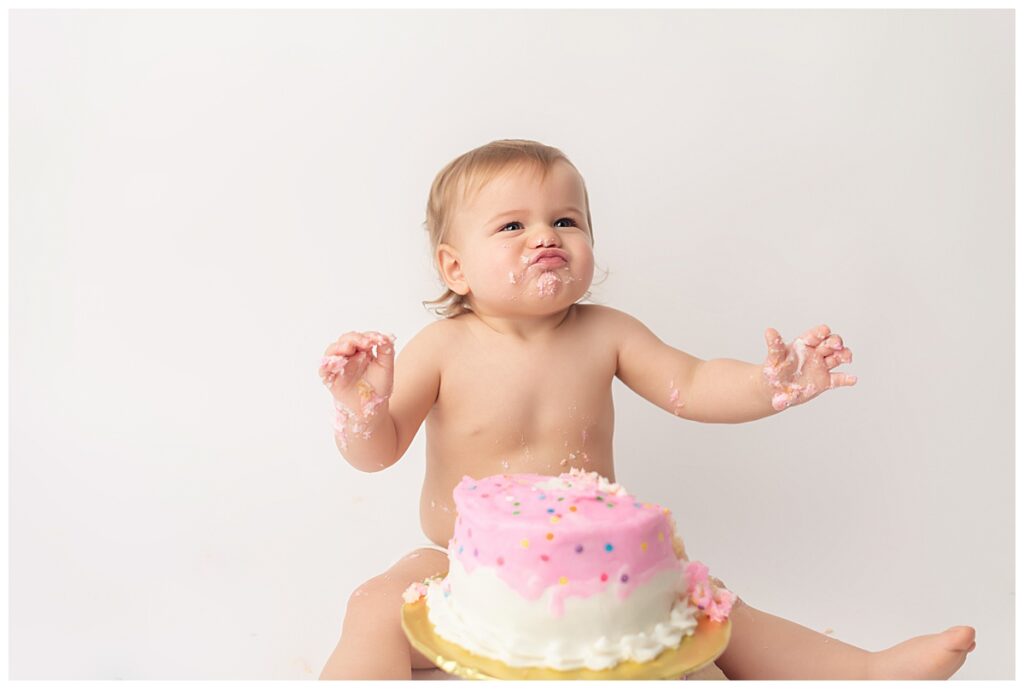 Baby girl smashing cake and making a scrunchy face