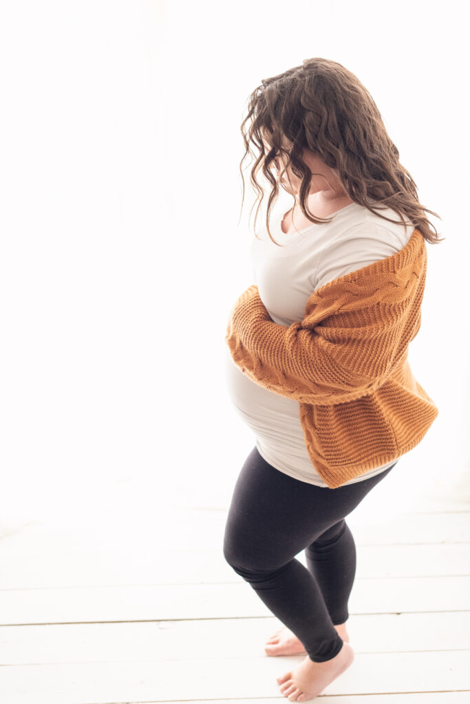 Pregnant Mom backlit wearing favorite mustard sweater