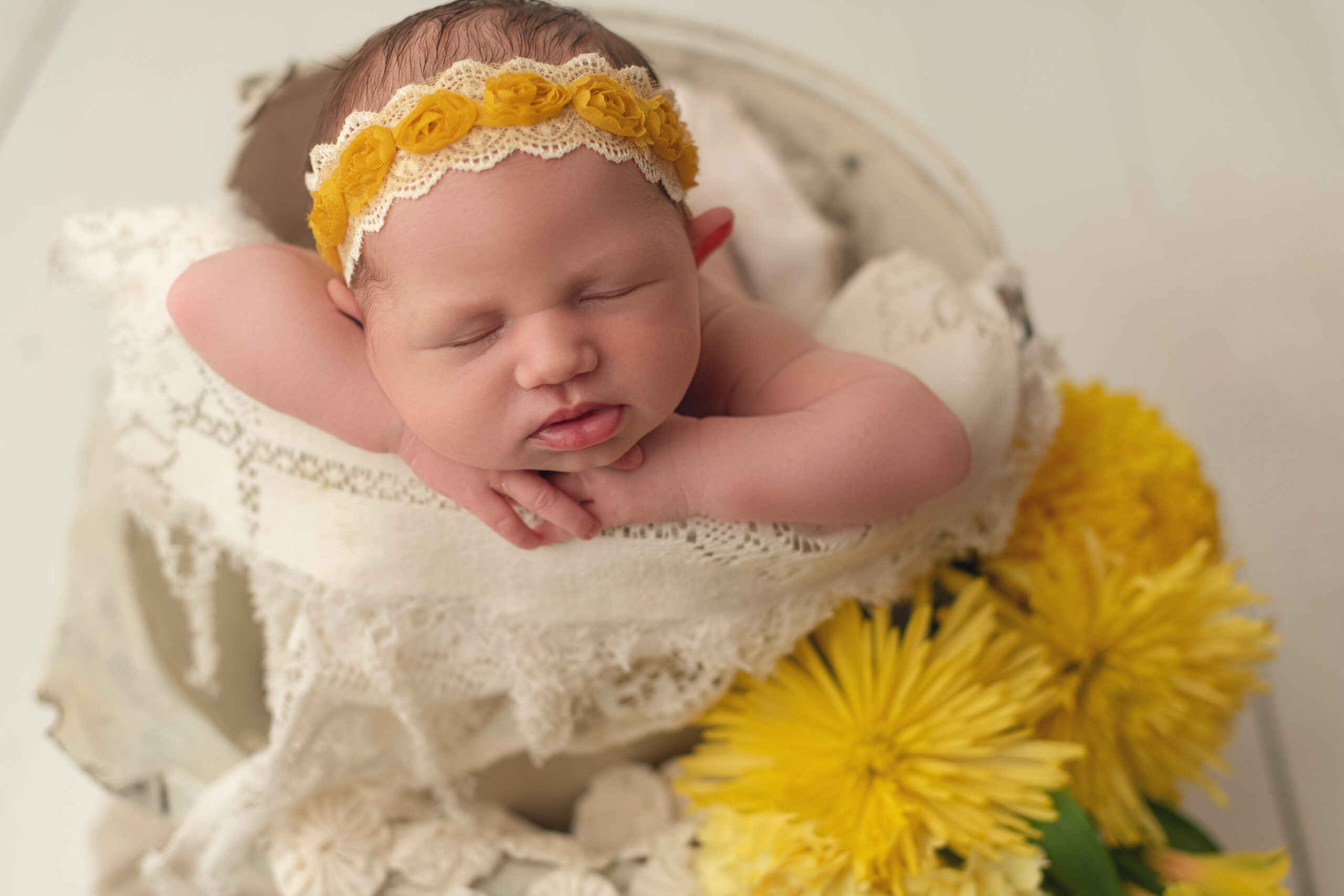 Baby girl in white vintage bucket in head one hands pose with yellow flowers surrounding her