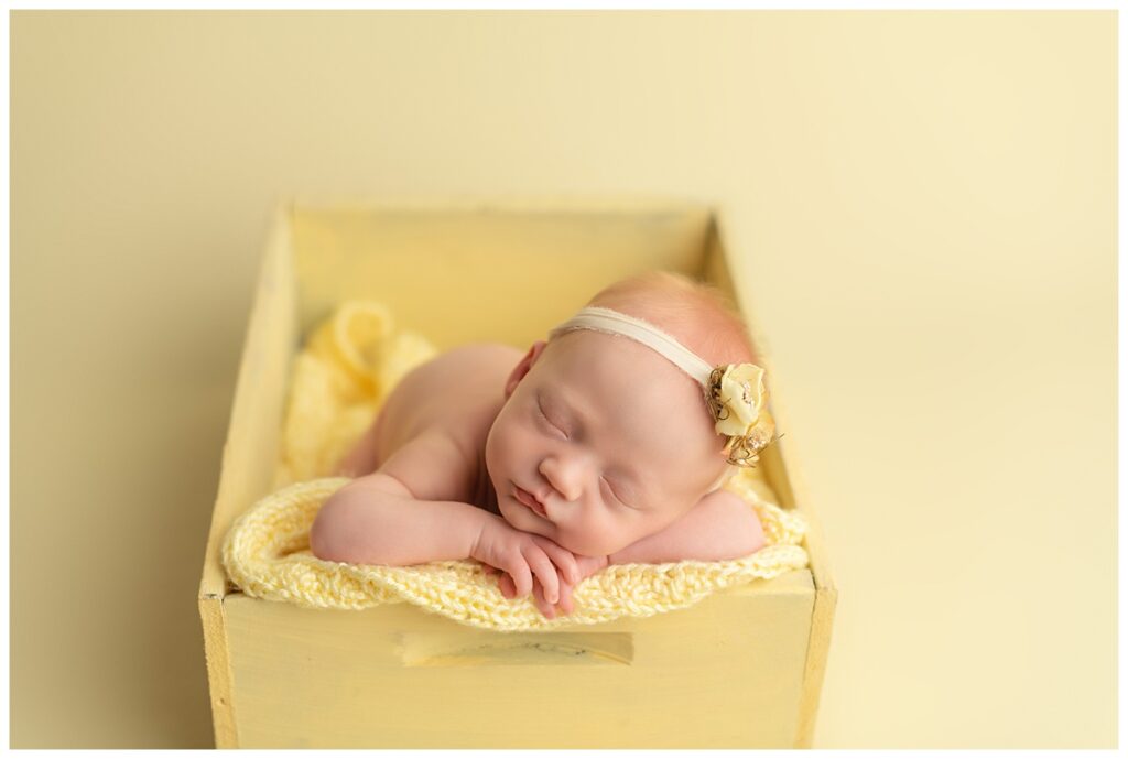 Newborn in rainbow colors. In yellow box on yellow backdrop