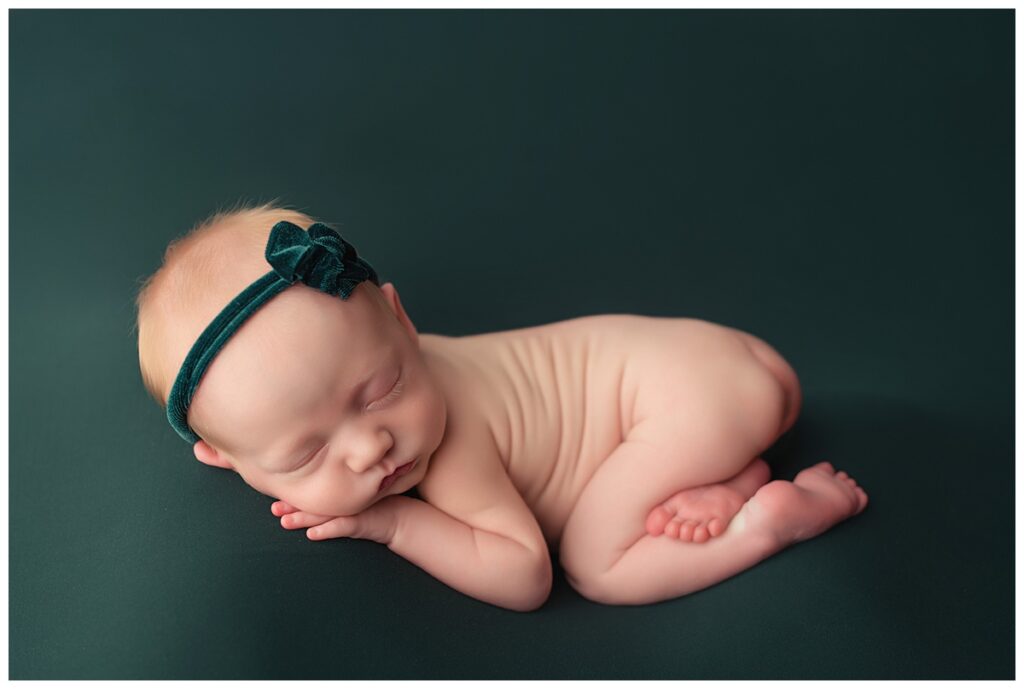 Newborn in rainbow colors. On green backdrop with green velvet bow