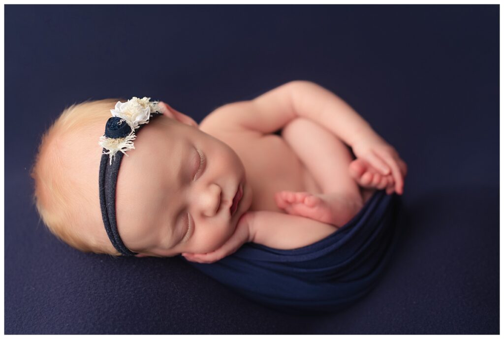 Newborn in rainbow colors. On blue backdrop with blue tieback and blue wrap